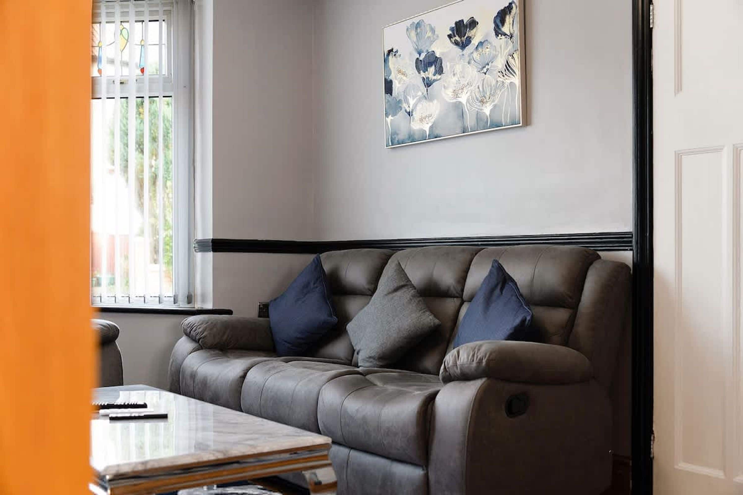 A living room with a sofa, a coffee table, and a painting on the wall.