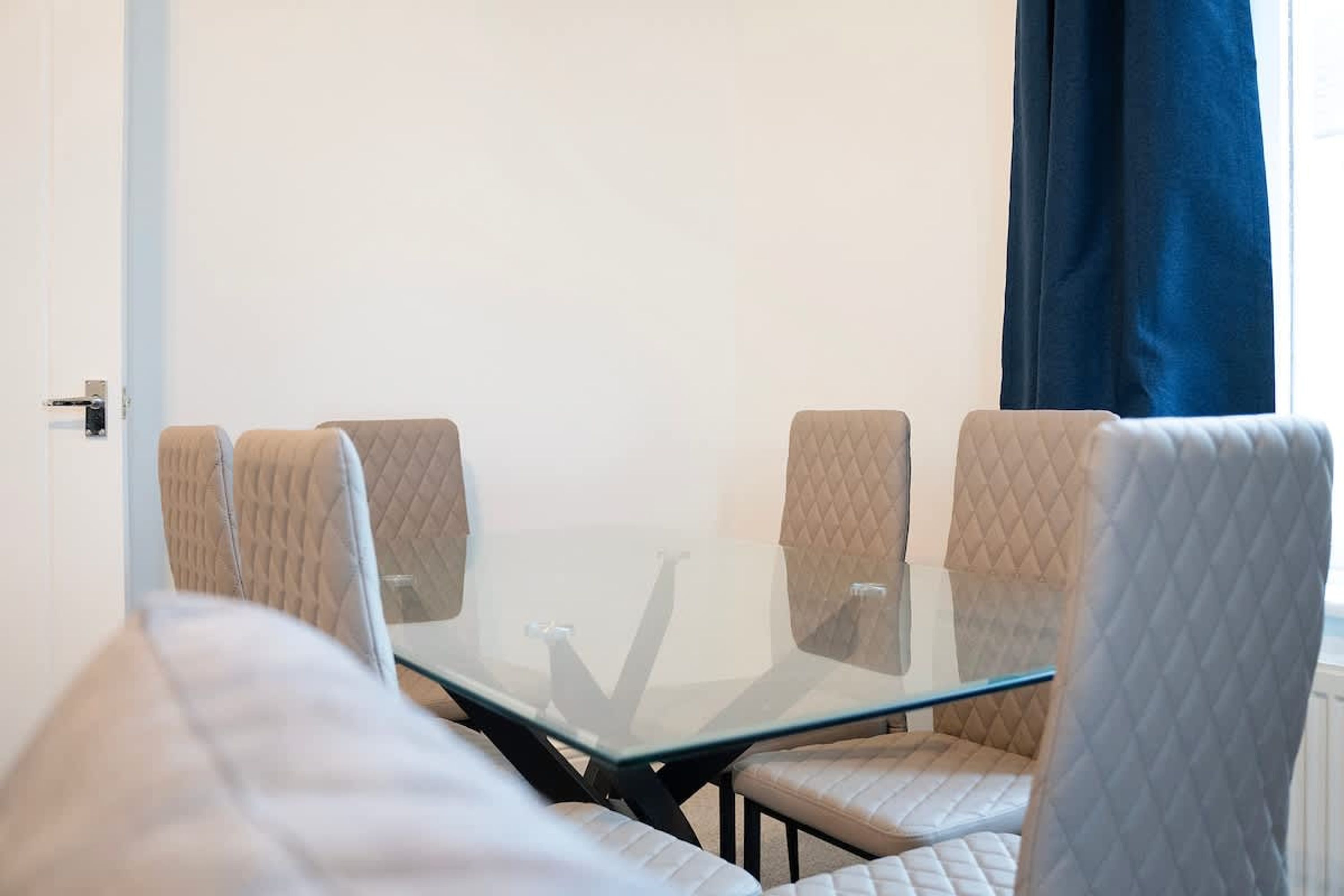 A conference room with a glass table and cushioned chairs.
