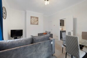 A modern living room with a grey sofa, a flat-screen TV, and a decorative wall piece. - Spacious 4 bed in North Shields With Free Wifi (North Shields)