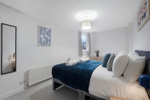 A modern bedroom with a bed, bedside table, and a window. - Spacious 4 bed in North Shields With Free Wifi (North Shields)