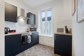 A modern kitchen with dark cabinetry, a microwave, and a kettle on the counter. - Spacious 4 bed in North Shields With Free Wifi (North Shields)