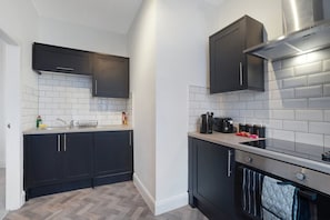 A modern kitchen with dark cabinetry, white subway tiles, and a stainless steel range hood. - Spacious 4 bed in North Shields With Free Wifi (North Shields)