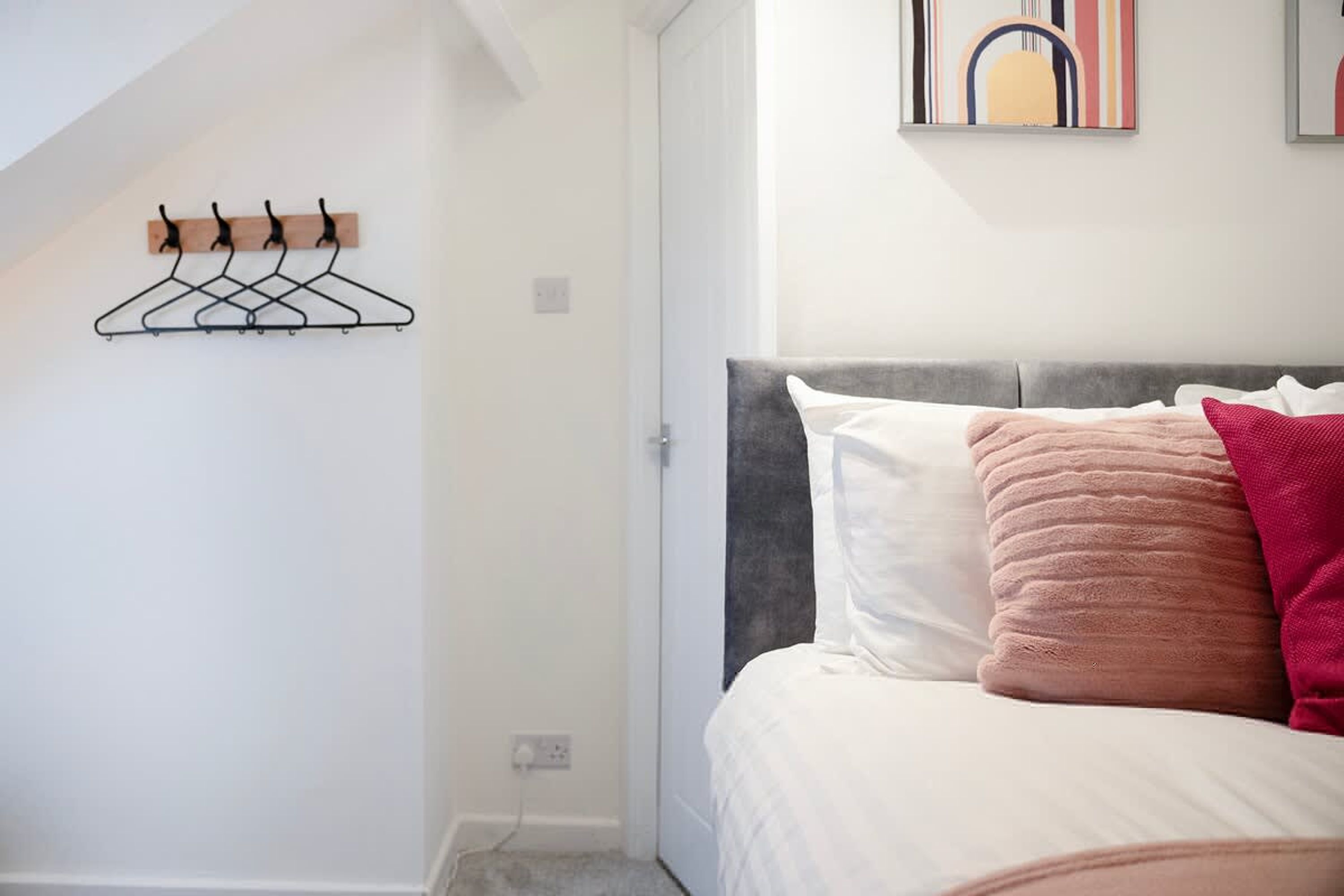 Ein Schlafzimmer mit einem Bett, einem Wandhaken für Kleidung und einem Gemälde.