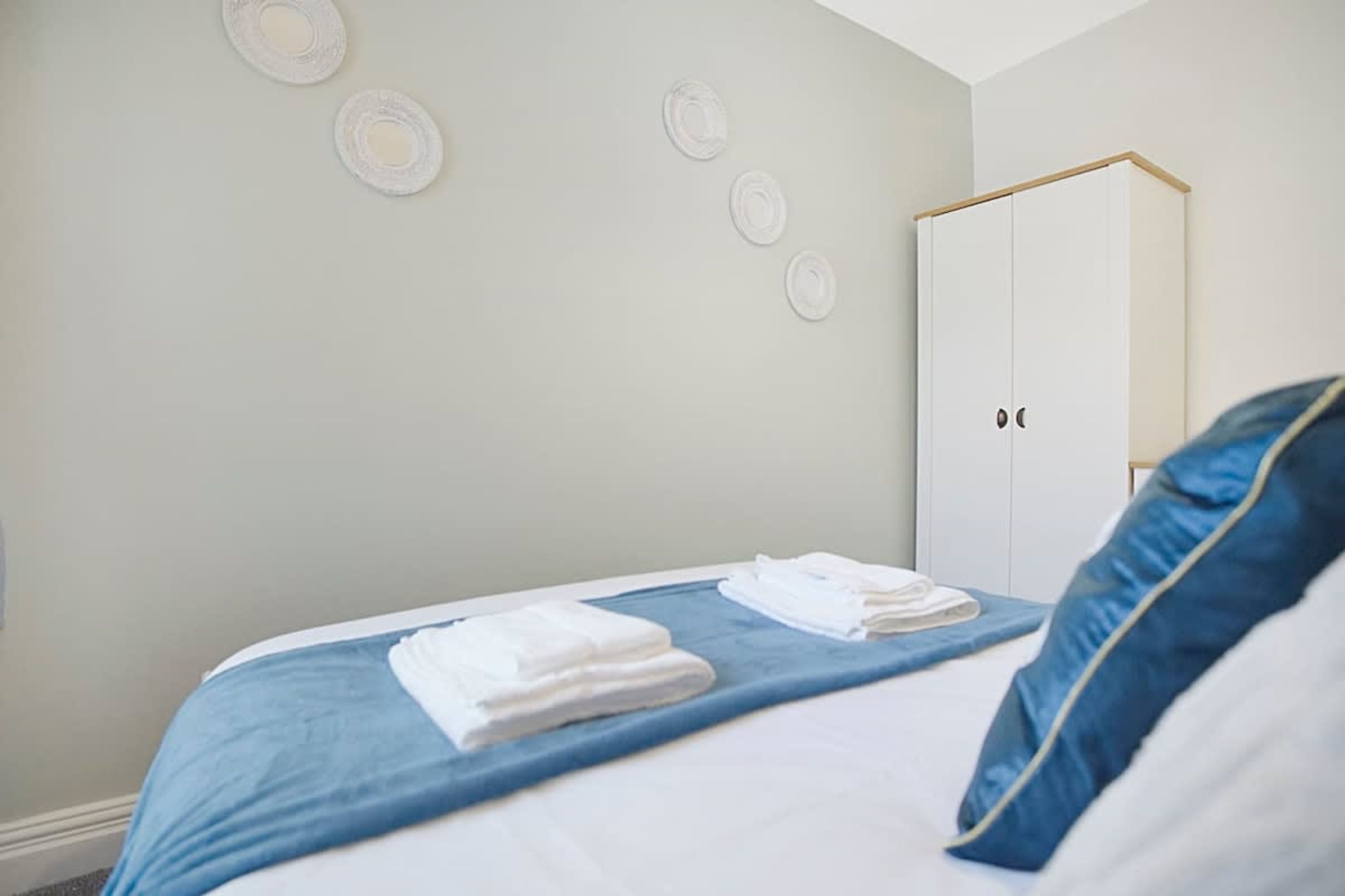 A bedroom with a bed, a wardrobe, and a wall with circular decorations.