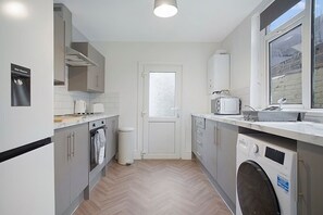 Une cuisine compacte équipée d’un lave-linge, d’un four à micro-ondes et d’un distributeur d’eau.