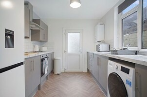 Una cocina compacta con lavadora, microondas y dispensador de agua.