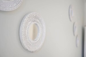 Una pared con un espejo circular y un plato decorativo.