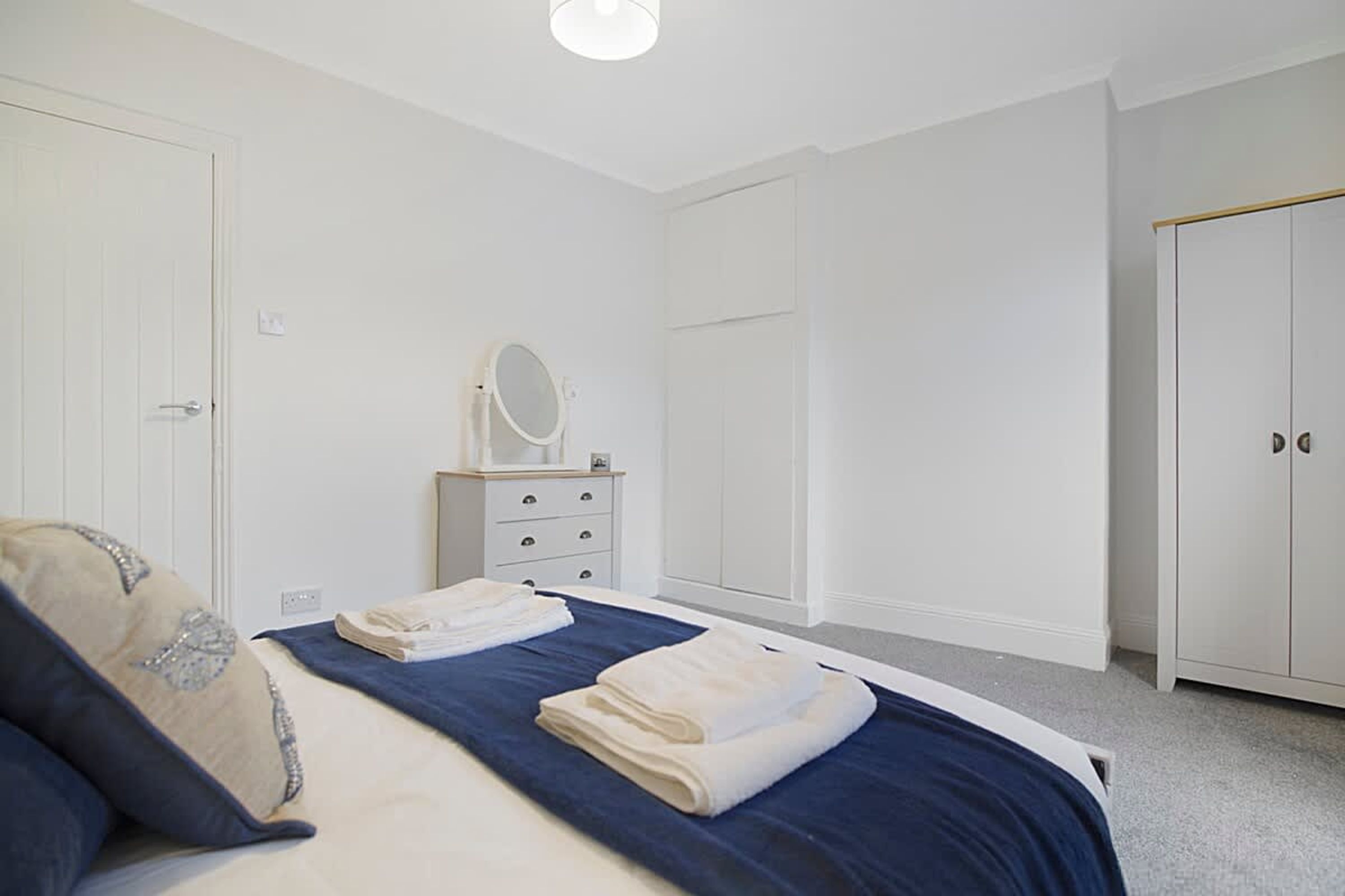 Une chambre à coucher comprenant un lit, une commode, un miroir et une armoire.