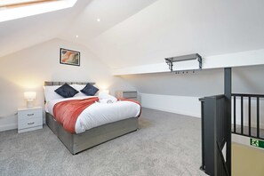 A bedroom with a bed, bedside tables, a nightstand, a ceiling light, a wall-mounted shelf, and a black railing. - Comfortable 4BR Stay Byerley Road by Stay With Us (Shildon)