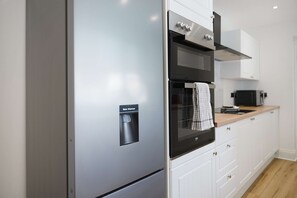 Una cocina moderna con refrigerador, horno y microondas integrados.