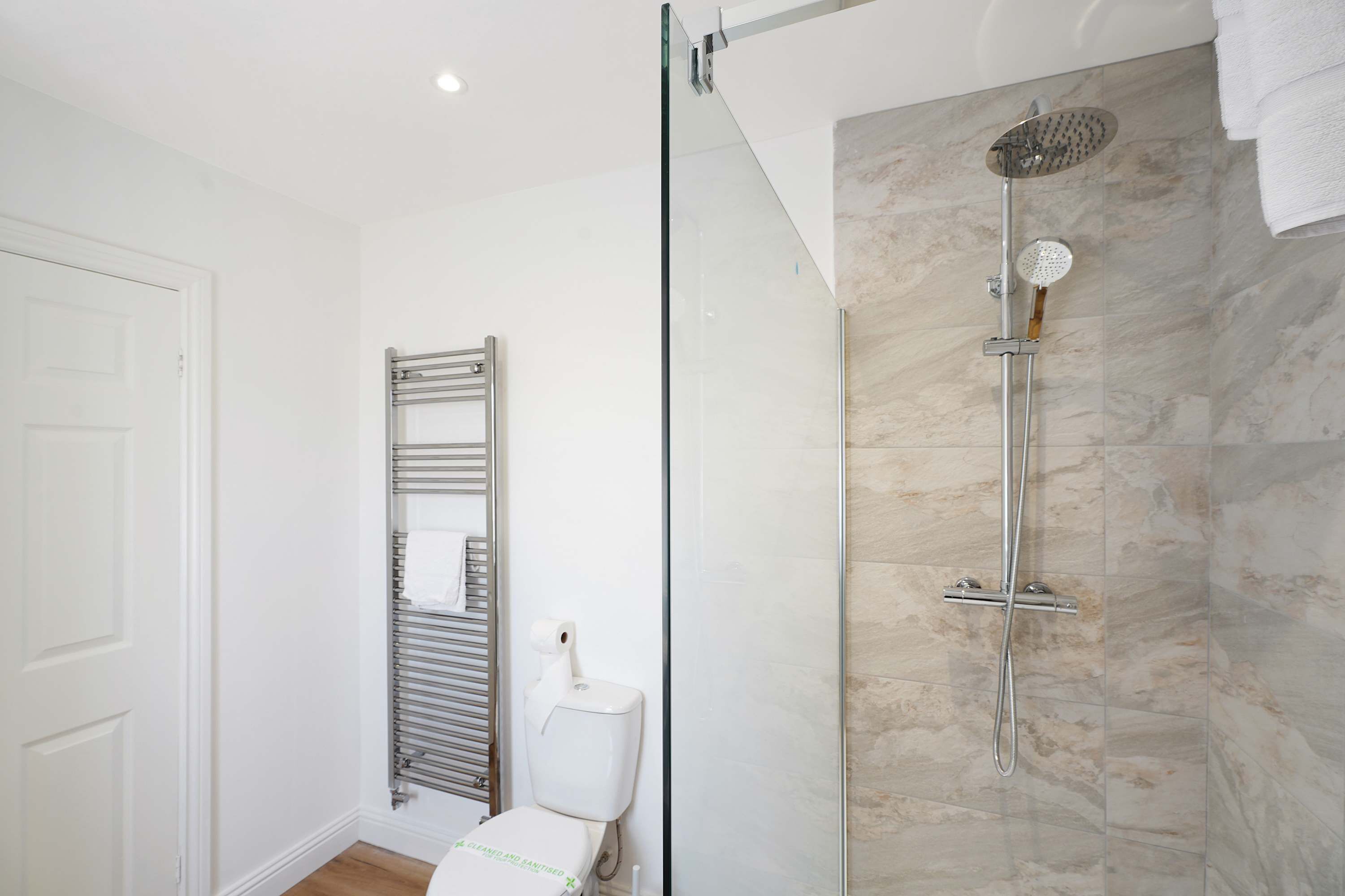 A modern bathroom with a glass-enclosed shower, a toilet, and a towel rack.