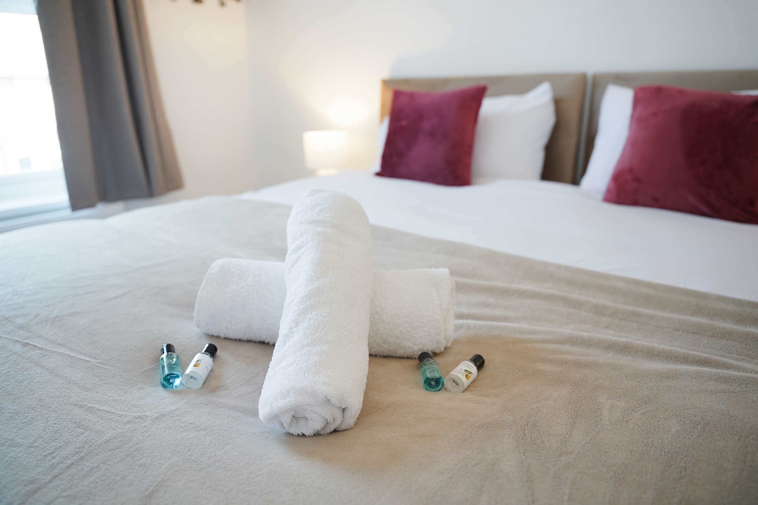 Une chambre d’hôtel avec un lit bien fait, deux serviettes pliées et deux flacons de produits de toilette.