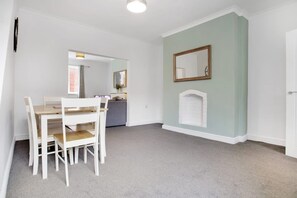 Um quarto com uma mesa de jantar e cadeiras, um espelho na parede e uma porta.