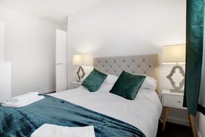 A neatly made bed with a white and teal duvet, two green pillows, and a matching teal throw blanket. - Comfortable Three Bedroom Family Apartment (Houghton le Spring)