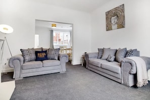 A living room with two grey sofas, a lamp, and a Buddha statue. - Comfortable Three Bedroom Family Apartment (Houghton le Spring)
