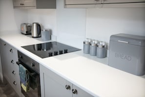 Uma cozinha com design moderno, com fogão embutido, máquina de pão e cafeteira.