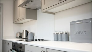 Una cocina moderna con horno empotrado, hervidor y panificadora sobre la encimera.