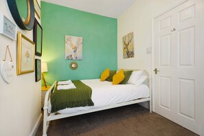 A bedroom with a bed, a green wall, and a white door. - Charming 3 Bed Steps From Redcar Beach and Station (Redcar)
