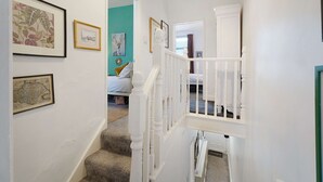 A hallway with a staircase leading to a bedroom with a bed and a window. - Charming 3 Bed Steps From Redcar Beach and Station (Redcar)