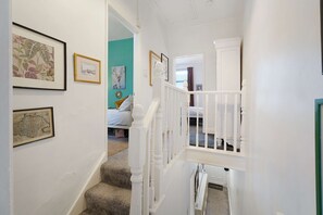 A hallway with a staircase leading to a bedroom with a bed and a window. - Charming 3 Bed Steps From Redcar Beach and Station (Redcar)