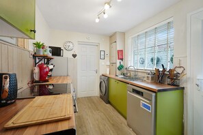 A compact kitchen with a microwave, kettle, and a sink with utensils. - Charming 3 Bed Steps From Redcar Beach and Station (Redcar)