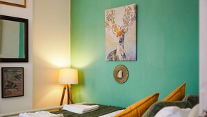 A hotel room with a bed, a bedside lamp, a framed picture, and a wall with a painting. - Charming 3 Bed Steps From Redcar Beach and Station (Redcar)