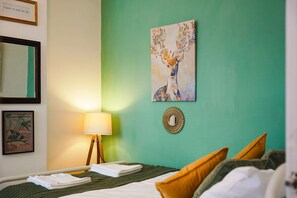 A hotel room with a bed, a bedside lamp, a framed picture, and a wall with a painting. - Charming 3 Bed Steps From Redcar Beach and Station (Redcar)