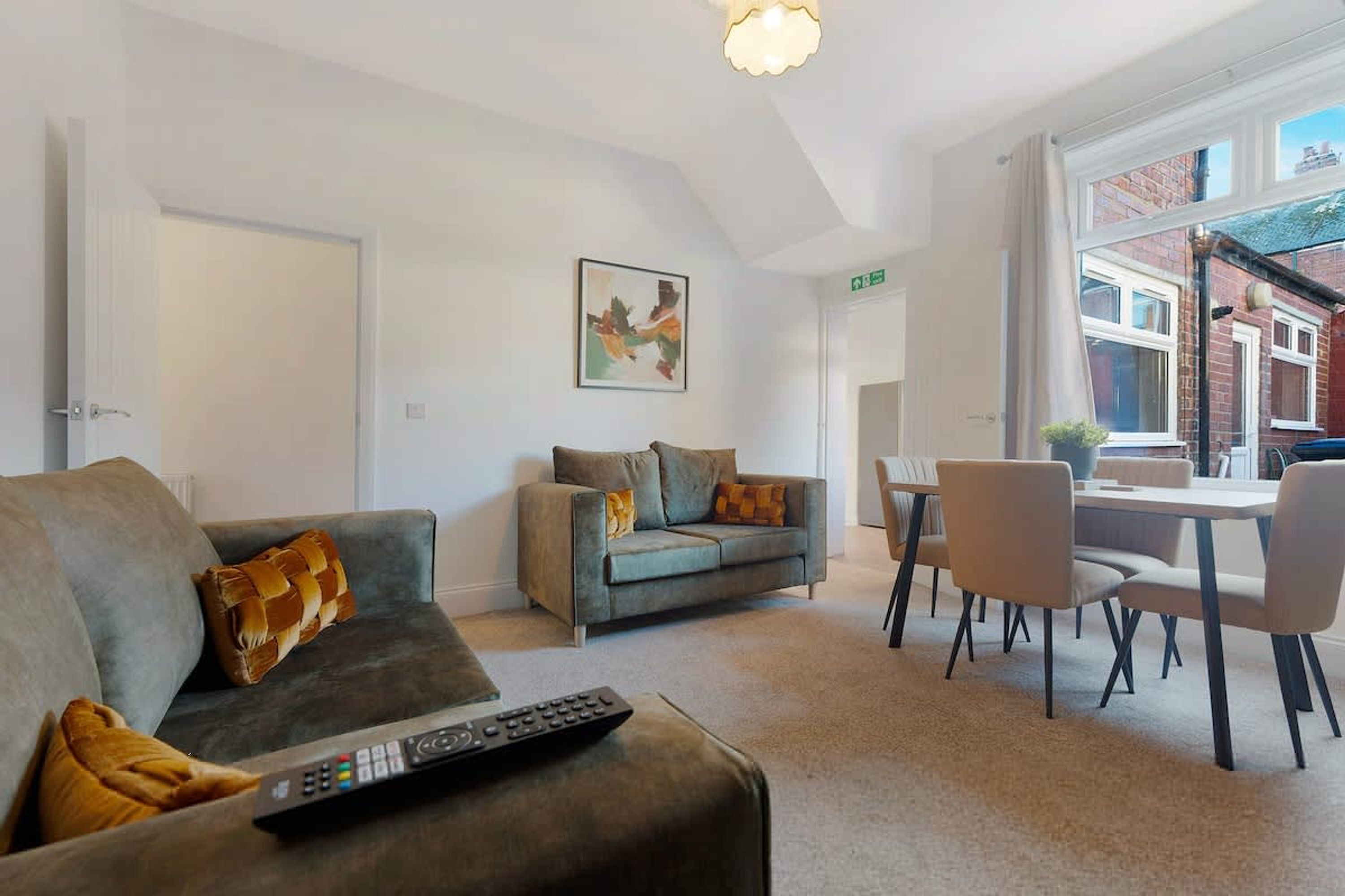 Un salon moderne avec un canapé gris, un plus petit canapé gris et un coin repas comprenant une table et des chaises.