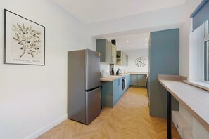 Una cocina moderna con refrigerador de acero inoxidable, armarios azul claro y piso de madera.