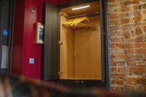 Une pièce avec une armoire en bois, un mur rouge et un mur en briques.