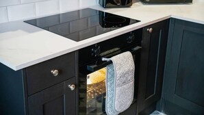 Una cucina con piano cottura a induzione nero, forno a microonde e forno ventilato.