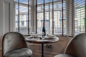 A corner room with a dining table, two chairs, and a view through large windows. - Boutique 1 Bedroom in Hartlepool With Fireplace (Hartlepool)