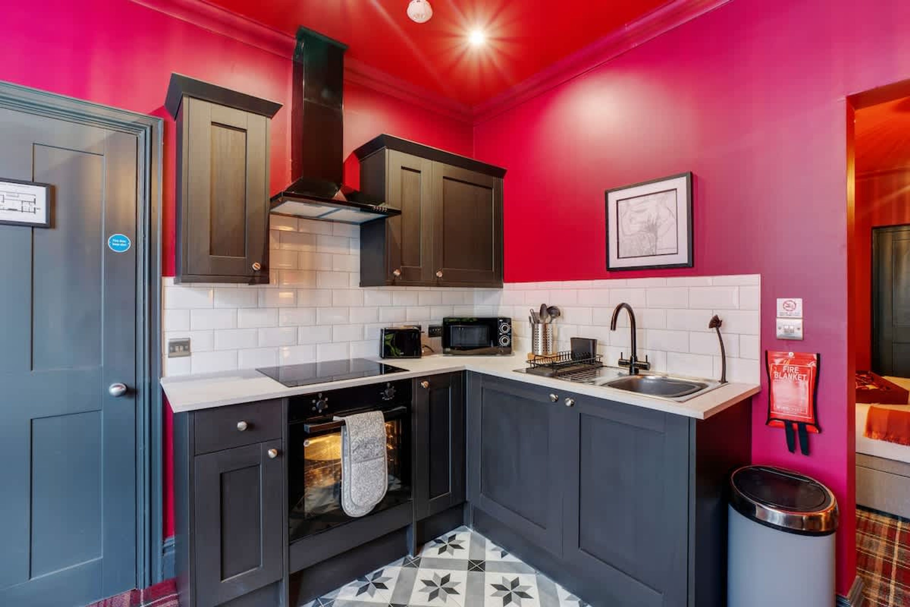 A compact kitchen with dark cabinets, a microwave, a stove, and a sink.