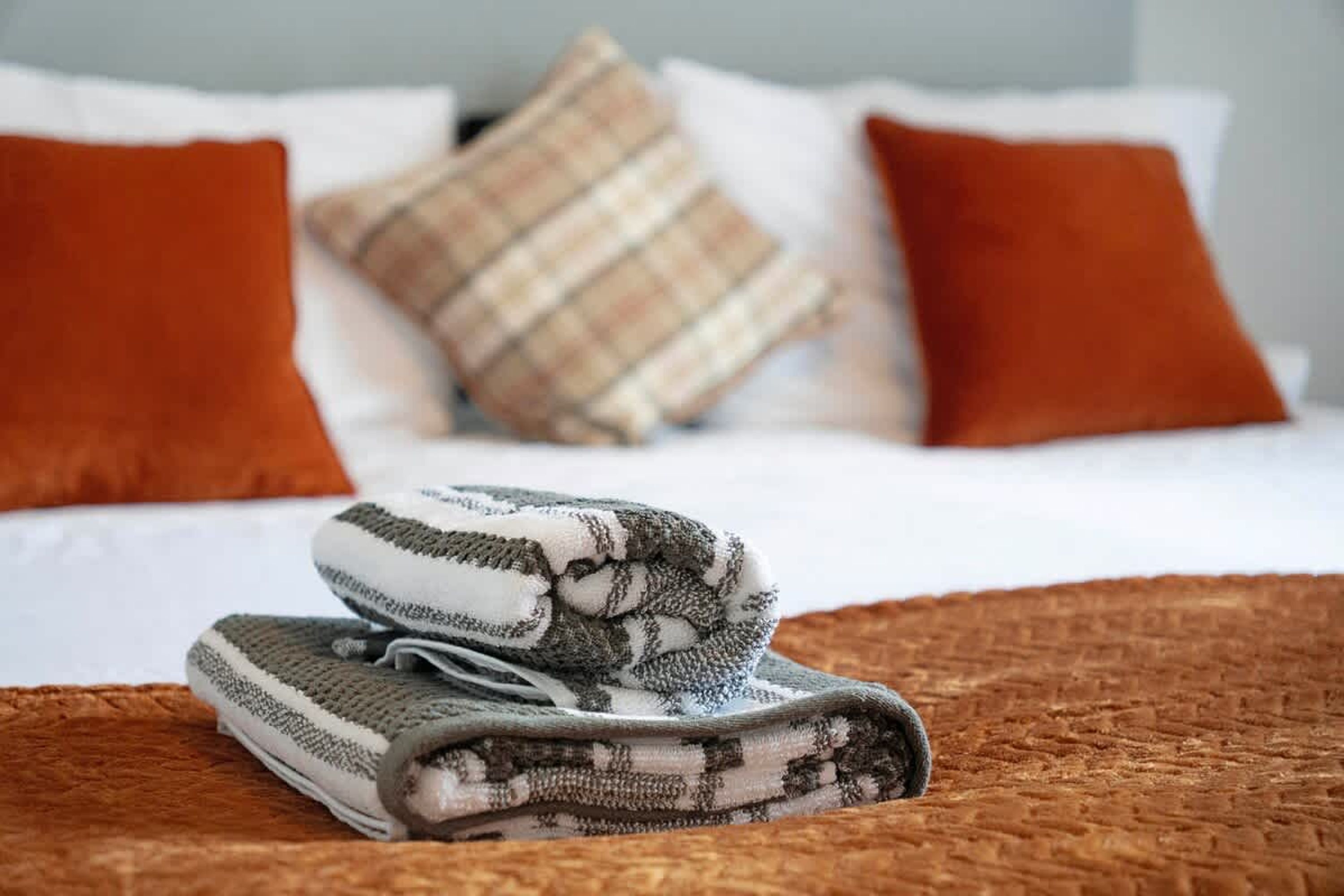 A neatly made bed with a folded blanket and pillows.