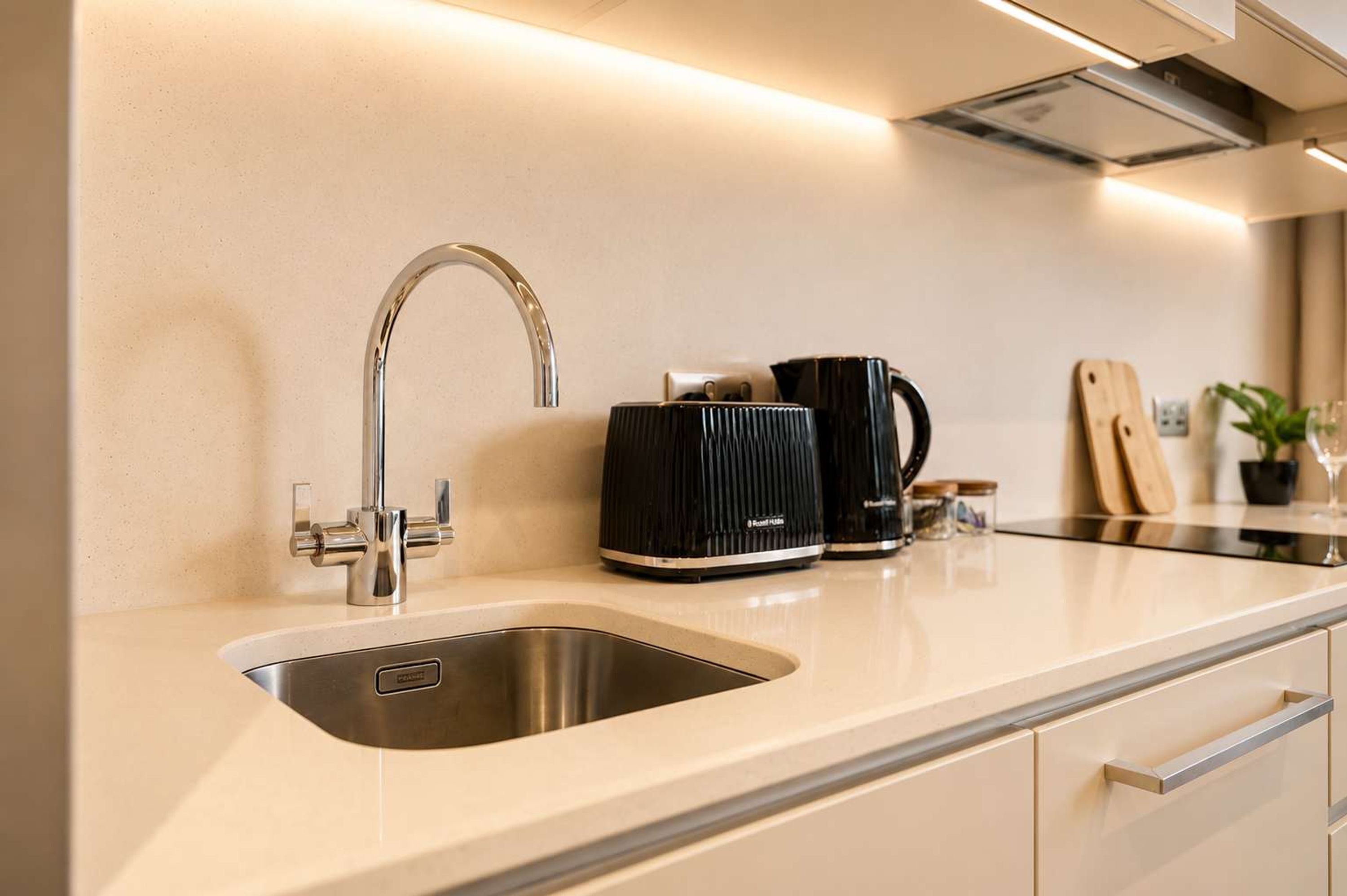 A modern kitchen with a stainless steel sink, a coffee maker, and a knife block on the countertop.
