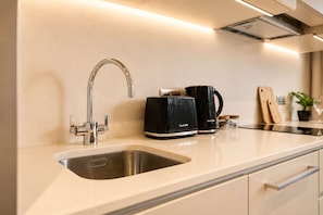 A modern kitchen with a stainless steel sink, a coffee maker, and a knife block on the countertop.