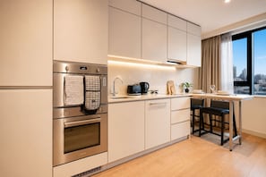 A modern kitchen with stainless steel appliances, a built-in oven, and a window with a city view. - Modern Studio by Stay With Us (Salford)