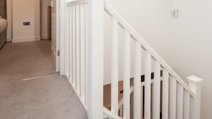Un escalier avec des rampes blanches menant à un palier.
