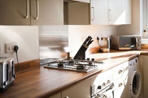 Eine Küche mit einem Gasherd, einem Toaster, einer Mikrowelle und einer Waschmaschine.