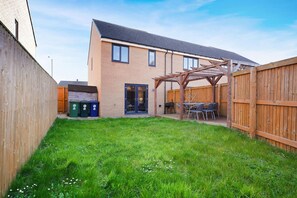 A residential backyard with a wooden fence, a patio with outdoor furniture, and a garage. - Modern Coastal Stay Minutes From Redcar Beach (Redcar)