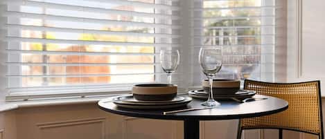 A dining area with a table set for two, two wine glasses, and plates.