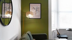 A room with a green wall, a framed picture, a floor lamp, and a window with blinds. - Hartlepool Marina Retreat 2BR Sleeps 4 by Stay With Us (Hartlepool)