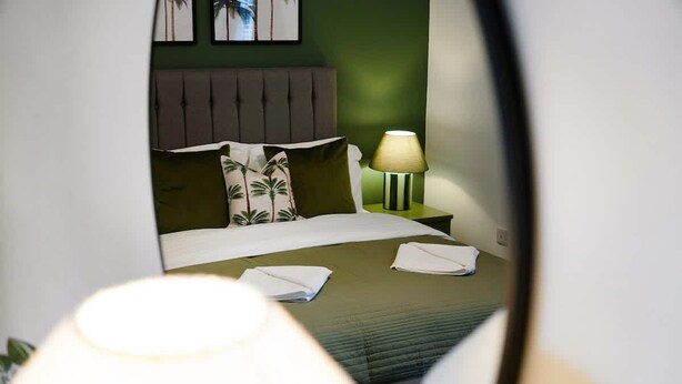 A hotel room with a bed, a nightstand with a lamp, and a wall with framed pictures. - Hartlepool Marina Retreat 2BR Sleeps 4 by Stay With Us (Hartlepool)