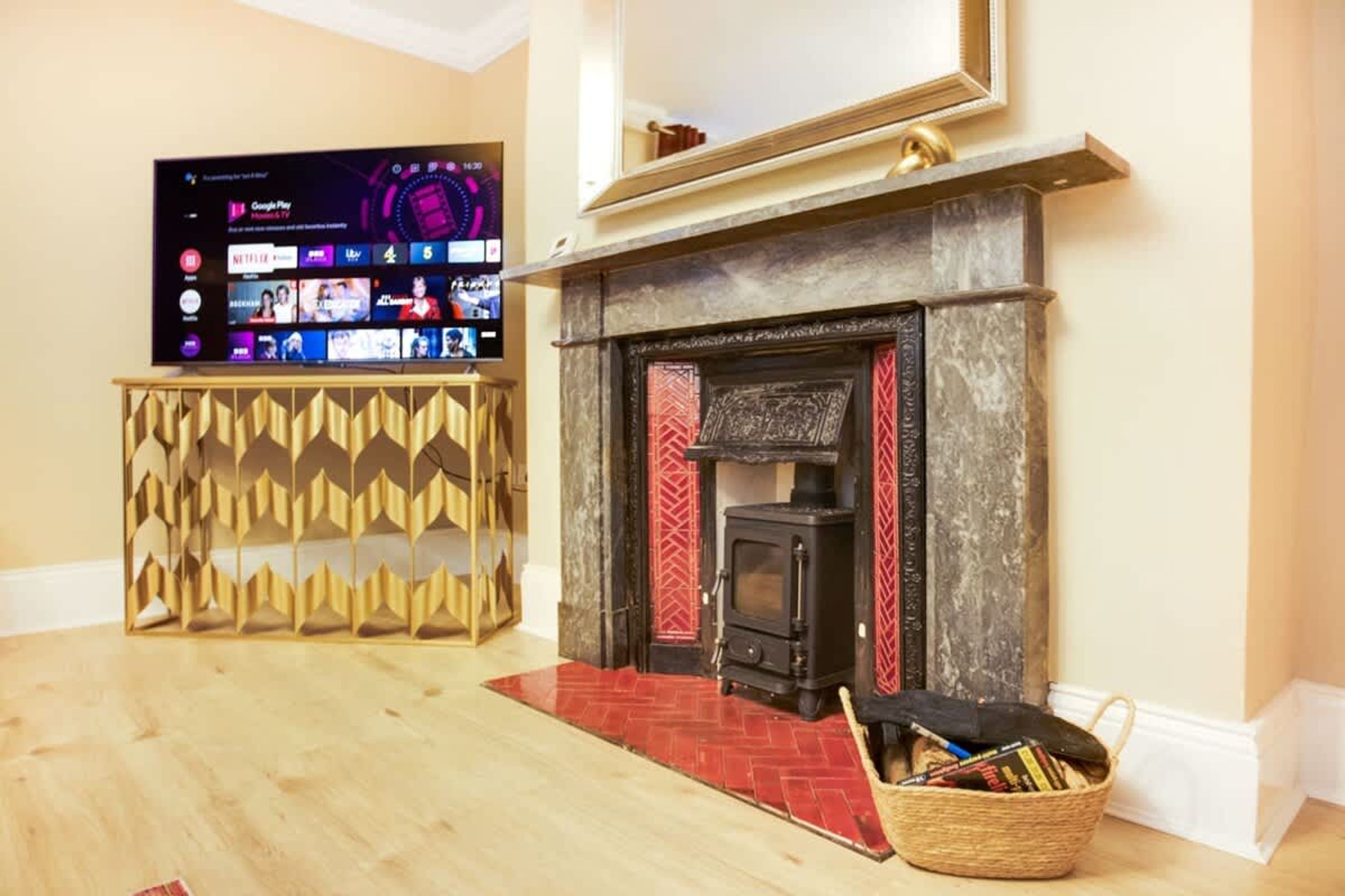 A room with a fireplace, a television mounted on a wall, and a wooden floor.