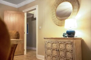 A hallway with a wooden door, a mirror with a decorative frame, and a lamp on a cabinet. - Luxurious Hot Tub Getaway Cottage Free Parking (Bishop Auckland)