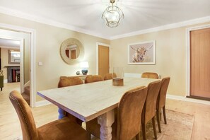 A dining room with a large wooden table, six upholstered chairs, a round mirror, a framed artwork, and a door. - Luxurious Hot Tub Getaway Cottage Free Parking (Bishop Auckland)