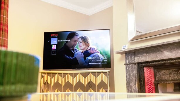 Ein an der Wand befestigtes Fernsehgerät zeigt die Netflix-Oberfläche mit dem Titel 'Virgin River'.