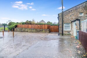 A wet outdoor area with a stone wall, wooden fence, and a building with a stone facade. - Luxurious Hot Tub Getaway Cottage Free Parking (Bishop Auckland)