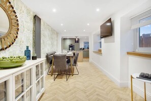 A modern kitchen with a dining area, a large mirror, and a television on the wall. - Luxurious Hot Tub Getaway Cottage Free Parking (Bishop Auckland)