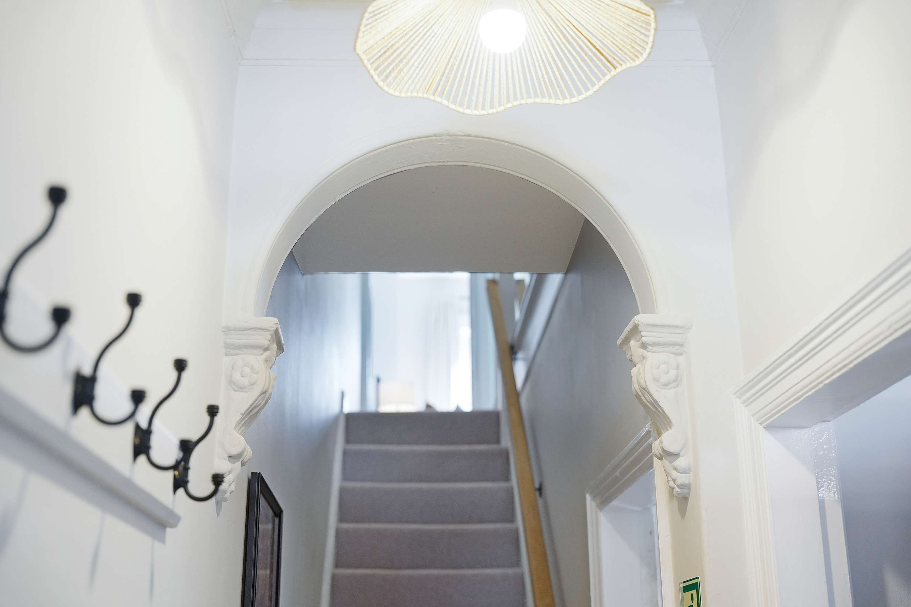 A staircase with a white railing, a chandelier, and a framed picture on the wall.